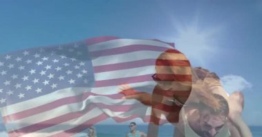 Amerikan bayrağı sallayarak plajda erkeğin sırtına tırmanan bir çift. Romantizm, eğlence, vatanseverlik, deniz kenarı, açık hava, neşe, macera