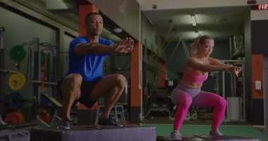 Fitness partnerlerinin dizlerini bükmesi, baygın kod örtüsünün ortasında güç için alternatif kutucuk atlamalarına neden oluyor. Atletizm, güç, güç, takım çalışması, motivasyon, modern, canlı