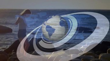 Kadın gün batımında sahile giriyor saçlarını tarıyor ve Asya-Pasifik 'i vurgulayan yörüngesel küreyi çalıştırıyor. Düşünce, huzur, doğa, dijital, fütüristik, teknoloji, manzara