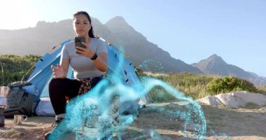 Kamp yerinde akıllı telefonları dinleyen bir kadın AR teknisyeninin mavi kurdele saran bacaklarını gösteriyor. Güçlendirilmişlik, vahşi doğa, macera, teknoloji, keşif, açık hava, yenilikçi