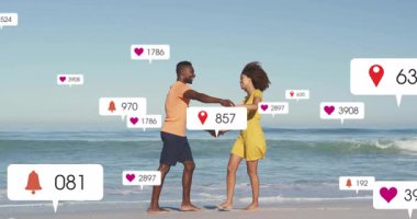 Yüzen sosyal medya simgeleri kontlar gibi güncellenirken çiftler el ele tutuşup sahilde dans ediyorlar. Romantizm, bağlantı, kutlama, dinginlik, hareket, sosyal medya, eğlence