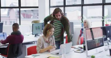 Kadın dizüstü bilgisayarı incelerken aynı zamanda iş verilerini gösterip işbirliği yapıyor. İşbirliği, takım çalışması, ofis, modern, analiz, üretkenlik, iletişim