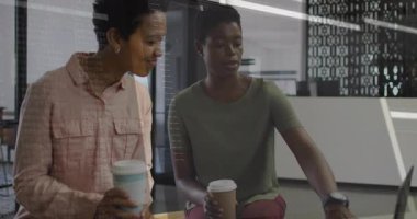 İki meslektaş kol saatine bakıyor ve bölüm kahvesini yudumlarken IT kodunu etkinleştiriyor. İşbirliği, yenilik, teknoloji, işyeri, iletişim, modern, başlangıç