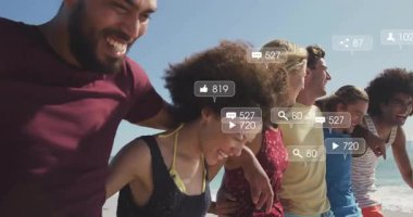 Arkadaşların kumsalda yürürken hareketli sosyal medya ölçümleri nişanlandıklarını gösteriyor. Plaj, arkadaşlık, sosyal medya, açık hava, yaşam tarzı, topluluk, mutluluk