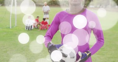 Kamera, kalecinin topu kolunun altına sakladığını ve futbol maçını işaret fişekleriyle hazırladığını gösteriyor. Sporcu, spor, yarışma, takım çalışması, kentsel, canlı, kararlı