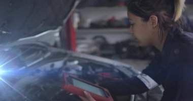 OBD kablosunu kaputun altındaki kırmızı tablete bağlayan kadın tamirci ve motor kontrolü için tarama kodları. Otomotiv, tanı, mekanik, teknoloji, sanayi, onarım, profesyonel