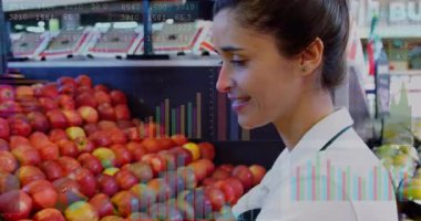 Market işçisi elmaları tarıyor satış grafiklerini örtüyor ve raflardaki fiyat etiketlerini düzenliyor. Taze üretim, perakende sektörü, görsel pazarlama, envanter yönetimi, süpermarket düzeni, müşteri hizmetleri, profesyonel çevre