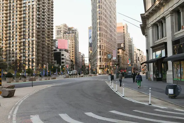 Flatiron binası düz dizaynlı kıvrımlı yol boyunca sokak saati ve saksılarıyla yükseliyor. Şehir, mimari, modern, sokak, ufuk çizgisi, şehir manzarası, tasarım