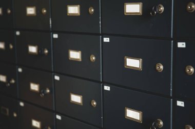 Metal kiralık kasalar düz dizaynlı ızgara duvarda, pirinç kilitler ve etiket yuvaları var. Güvenlik, depolama, endüstriyel, minimalist, organizasyon, kasa, gizlilik