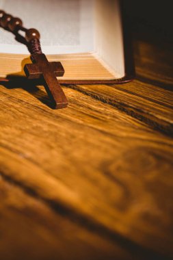Bible kept on wooden flooring with rosary beads