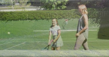 Gri bluz, etek, raket, top ve ağla çimen kortunda kızına antrenman yaptırıyor. Spor, koçluk, aile, eğlence, açık hava, atletizm, eğitim