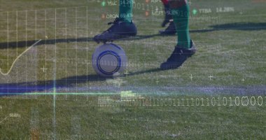 Guiding legs wearing black cleats controlling soccer ball on grass pitch, with digital overlay. Athleticism, sportswear, digital, analytical, innovation, agility, outdoor
