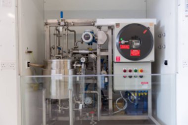 Endüstriyel işlem ünitesinde paslanmaz çelik tank, borular, göstergeler, camın arkasındaki kontrol dolabı var. Otomasyon, üretim, mühendislik, makine, enstrümantasyon, endüstriyel tasarım, teknoloji