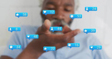 Mavi tişörtlü bir adam odada bildiri ikonlarını üflüyor. Yürek yorumu seven takipçileri var. Dijital semboller, yaşlanma, teknoloji, minimalizm, sosyal ilişki, iletişim, kullanıcı arayüzü