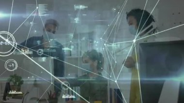 Ofisteki ekip iş verilerini, holografik çizelgeleri ve grafikleri gösteren erkek olarak inceliyor. İşbirliği, dijital arayüz, veri görselleştirme, takım çalışması, gelecekçilik, ofis ortamı, analitik