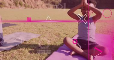 Çimenli alanda yoga minderlerini açan iki çocuk pembe kaplamalı sağlık için meditasyona giriyorlar. Açık hava, sağlık, dinginlik, dostluk, farkındalık, doğa, sükunet