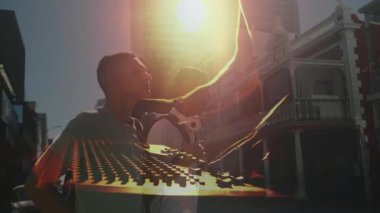 DJ kaygan fader senkronizasyon mikseriyle gitarist tıngırdatma akoru müzik prodüksiyonu için lens alevi altında. Müzik, işbirliği, kentsel, canlı, dinamik, performans, eğlence