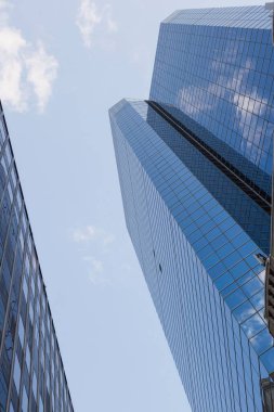 Düz mavi cam gökdelen, ofis binasının yanındaki bulutları yansıtıyor. Kopya alanı. Modern, mimari, kurumsal, minimalist, kentsel, gösterişli, geometrik