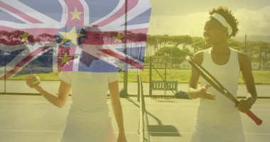 Gülen tenisçiler raket ve topu açık havada sert kortta bayrak kaplamalarıyla tutuyorlar. Spor, rekabet, atletizm, boş zaman, açık hava, canlılık, takım çalışması