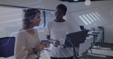 Bilgisayarlı ekranı gösteren iki kadın kahve fincanıyla modern ofiste dijital çizelgeleri tartışıyorlar. İşbirliği, teknoloji, analitik, iletişim, profesyonel, modern, üretkenlik