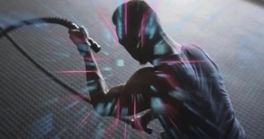 Spor salonundaki erkek sporcu halatları sıkıyor ve dijital izleme için dalgaları kamçılıyor. Fitness, strength, digital, technology, training, motion, energy