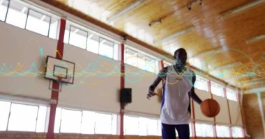 Erkek basketbolcu orta sahada top sürmeye başlıyor, atlıyor ve dalga boyu ile sayı yapıyor. Spor, fitness, atletizm, spor salonu, rekabet, eğitim, hareket