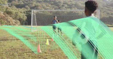 Futbol topunu tutan çocuk, futbol antrenmanındaki dokuma konilerini tamamladıktan sonra takım arkadaşının adımlarını izliyor. Atletizm, takım çalışması, çeviklik, sportmenlik, açık hava, rekabetçi, eğitim