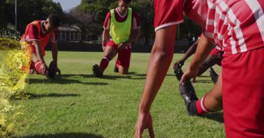 Futbolcular ısınma turlarında diz çökerek ayaklarının etrafında dönen altın parçacık halkalarını aktifleştiriyorlar. Atletik, takım çalışması, egzersiz, canlı, enerji, spor, açık hava