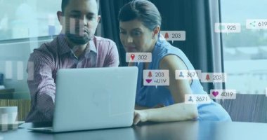 Meslektaşlar dizüstü bilgisayara eğilip yükselen sosyal medya simgelerini izliyor, pazarlama ölçümlerini gözden geçiriyorlar. İşbirliği, analitik, strateji, dijital pazarlama, iletişim, profesyonel, teknoloji