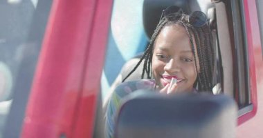 Dikiz aynası kullanan ve kırmızı araba makyajına pembe ruj süren bir kadın. Güzellik, bencillik, zarafet, moda, yaşam tarzı, minimalizm, güven