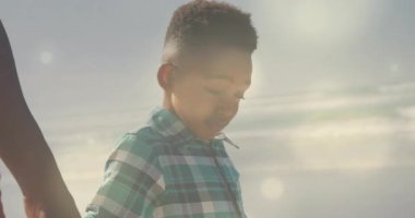 Baba, oğluna gün ışığında kumsalda yürüme rehberliği yapıyor. Sağlık yararlarını ön plana çıkarmak için dans eden mercekler. Aile, arkadaşlık, açık hava, macera, sıcaklık, bağlantı, doğal