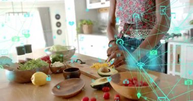 Yakın plan kadın avokadoyu yarıya indiriyor, ahşap tahtada biber doğruyor, akıllı mutfak simgelerini aktifleştiriyor. Aşçılık, aşçılık, modern, sağlıklı, yaşam tarzı, dijital, taze üretim