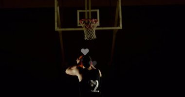 Basketbolcu topu göğsünde tutuyor ve yüzen kalplerle potaya şut atmaya çalışıyor. Sporcu, motivasyon, dinamik, spor, siluet, odaklanma, kararlılık