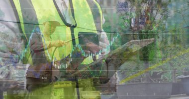 Gözlem ekibi yelek giyiyor tableti kontrol ediyor ve seradaki hortumla, şamdan çizelgesiyle suluyor. Tarım, bahçıvanlık, sürdürülebilirlik, yenilik, büyüme, çevre, profesyonellik