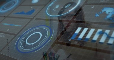 Gömlek ve gözlük takan adam masadaki holografik arayüzü kalem ve not defteriyle analiz ediyor. Futuristik, teknoloji, veri görselleştirme, iş, yenilik, dijital, çalışma alanı