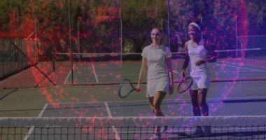 Beyaz elbiseli iki tenisçi dışarıda raketlerle sohbet edip gülümsüyor. Atletizm, takım çalışması, eğlence, sportmenlik, rahatlık, aktif giysi, canlı.