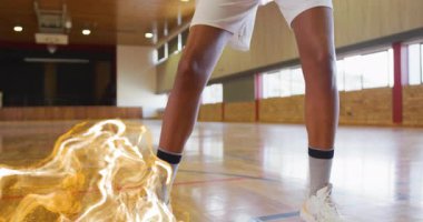 Basketbolcu sahada top sürüyor, topun etrafındaki altın aura 'yı harekete geçiriyor ve topu kaldırıyor. Sporcu, spor, enerji, hareket, odaklanma, kararlılık, yoğunluk