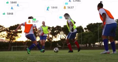 Kadın futbolcular spor eğitimleri sırasında yuvarlanan topa yüzen sosyal simgelerle yaklaşıyorlar. Atletizm, takım çalışması, fitness, açık hava, aktif, rekabetçi, motivasyon