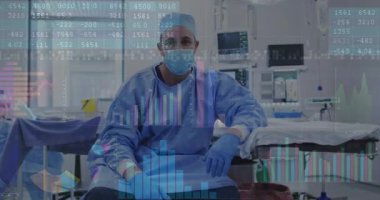 Ameliyathanede ameliyat masasının yanında erkek cerrah. Kolunu ayarlıyor ve analiz için veri tablolarını canlandırıyor. Tıbbi, analiz, görselleştirme, dijital, kesinlik, sağlık, teknoloji