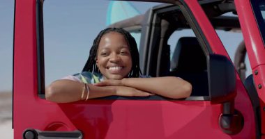 Kadın sürücü plaj alanına giriyor pencereyi indiriyor, dalga simgeleri sörf macerasını vurguluyor. Macera, boş zaman, açık hava, yaz, özgürlük, seyahat, yaşam tarzı