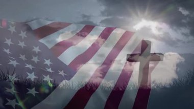 Güneşle tetiklenen Amerikan bayrağı çimenli sırtta statik haç üzerinde sallanıyor, yanıp sönen parlayan parlaklıklar. Vatanseverlik, açık hava, sembolizm, inanç, miras, doğa, huzur