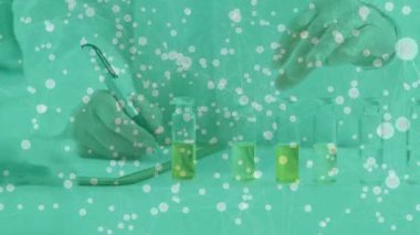 Bilim adamı deney tüplerini sarı test tüpleriyle dolduran deney tüplerini kaldırıyor, notlar yazıyor ve deneye hazırlanıyor. Araştırma, yenilik, kesinlik, kimya, profesyonel, deney, bilim