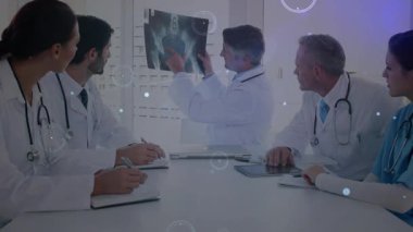 Tıbbi ekip hastane odasındaki masadan pelvik röntgen filmlerini alıyor. Kalça eklemini grafiklerle gösteriyor. İşbirliği, sağlık, tanı, dijital yenilik, profesyonellik, takım çalışması, tıbbi teknoloji