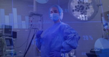 Cerrah maskeye dokunuyor ve veri tabloları güncellenirken gülümsemeyi göstermek için ameliyathanede çıkartıyor. Tıbbi, sağlık, profesyonellik, yenilik, kesinlik, teknoloji, klinik