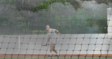 Tenis kortu, ağ ve çitlerde saç bandı takmış tenis raketi sallayan bir sporcu. Spor, atletik, aksiyon, fırtınalı, açık hava, dinamik, rekabet