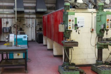 İki yeşil matkap, düz dizayn atölyesinde kırmızı dolaplar, çalışma tezgahları ve kanallarıyla duruyor. Sanayi, üretim, makine, inşaat, mühendislik, atölye, otomasyon