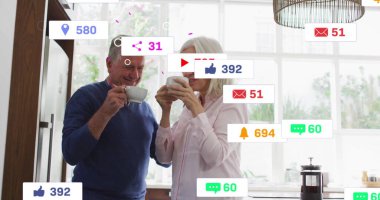 Mavi kazaklı ve pembe bluzlu bir çift mutfaktan kahve yudumluyor, yüzen bildirim simgeleriyle. Son sınıf, çift, evcil, modern, rahat, yaşam tarzı, sağlık