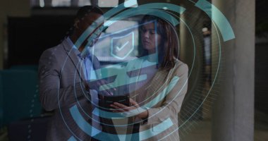 Ofis koridorunda tableti inceleyen takım elbiseli iki meslektaş holografik güvenlik örtüsüyle birlikte. Şirket, teknoloji, modern, işbirliği, dijital, fütüristik, profesyonel