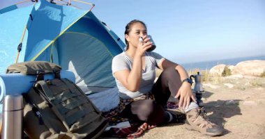 Moka pot demlemeyi bitirirken, çadır kaldırma bardağının yanında kamp yapan, açık hava pazarlaması için kahvesini yudumlayan. Macera, açık hava, manzara, sükunet, keşif, boş zaman, kırsal