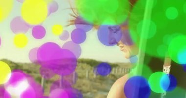 Seyahat pazarlamasında kumulların üzerine eğilen bir kadın. Kabarcık kaplamasına bakıp, saati kontrol ediyor. Sahil, eğlence, canlı, açık hava, yaşam tarzı, refah, tarz